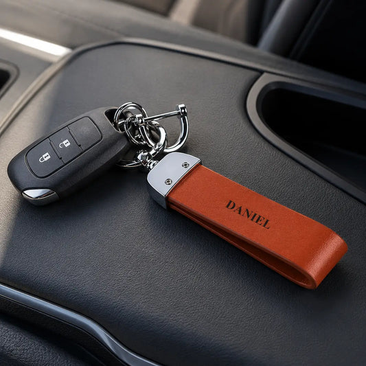 Personalised tan leather keychain engraved with DANIEL attached to car keys on vehicle centre console
