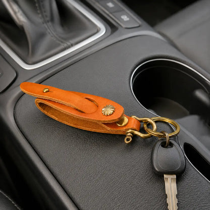 Orange leather key holder attached to car keys on vehicle centre console