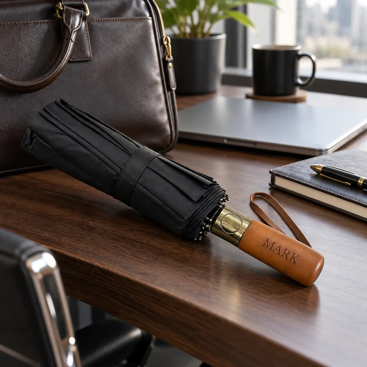 Personalised black folding umbrella with wooden handle engraved Mark on office desk with laptop and briefcase