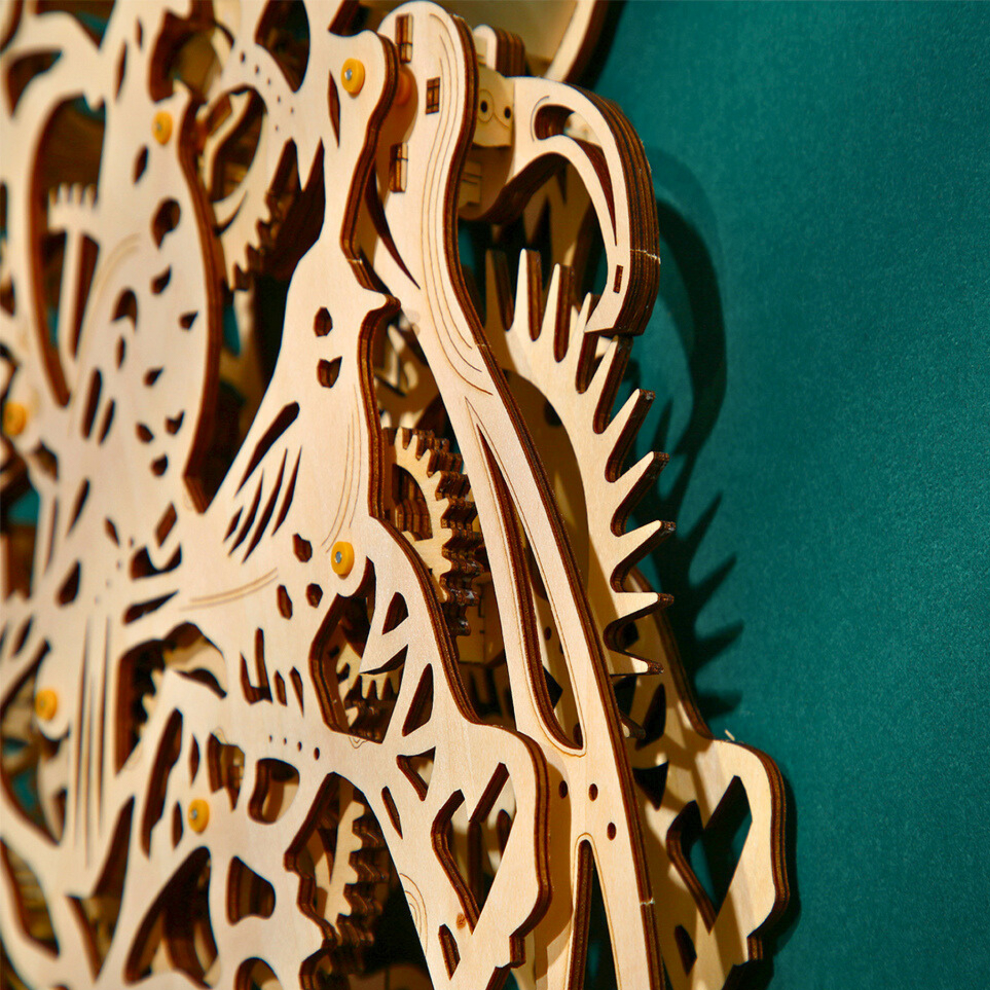 Wooden mechanical puzzle of a wall clock against a teal background