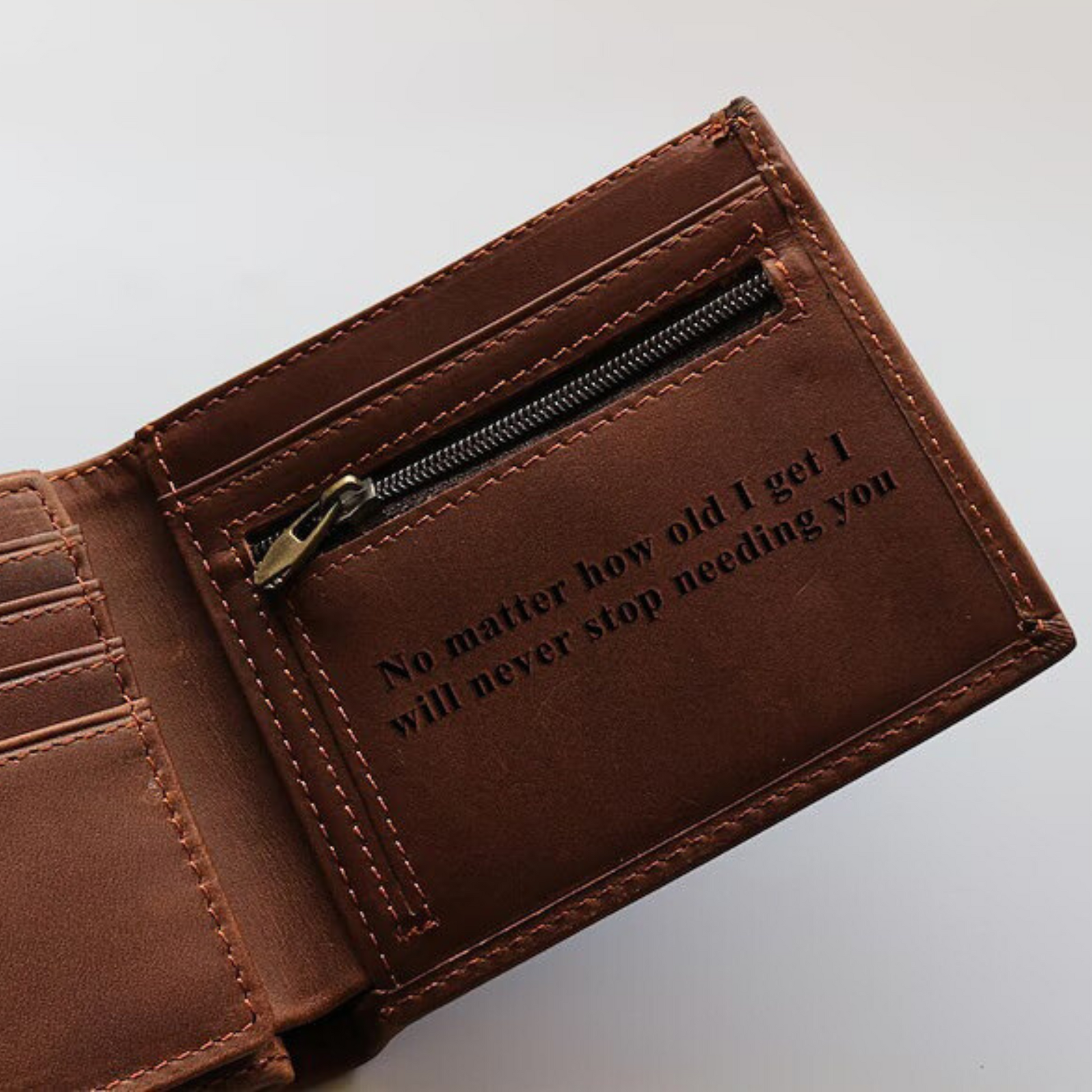 Brown leather wallet with engraved text and a zipped pocket to securely store money.