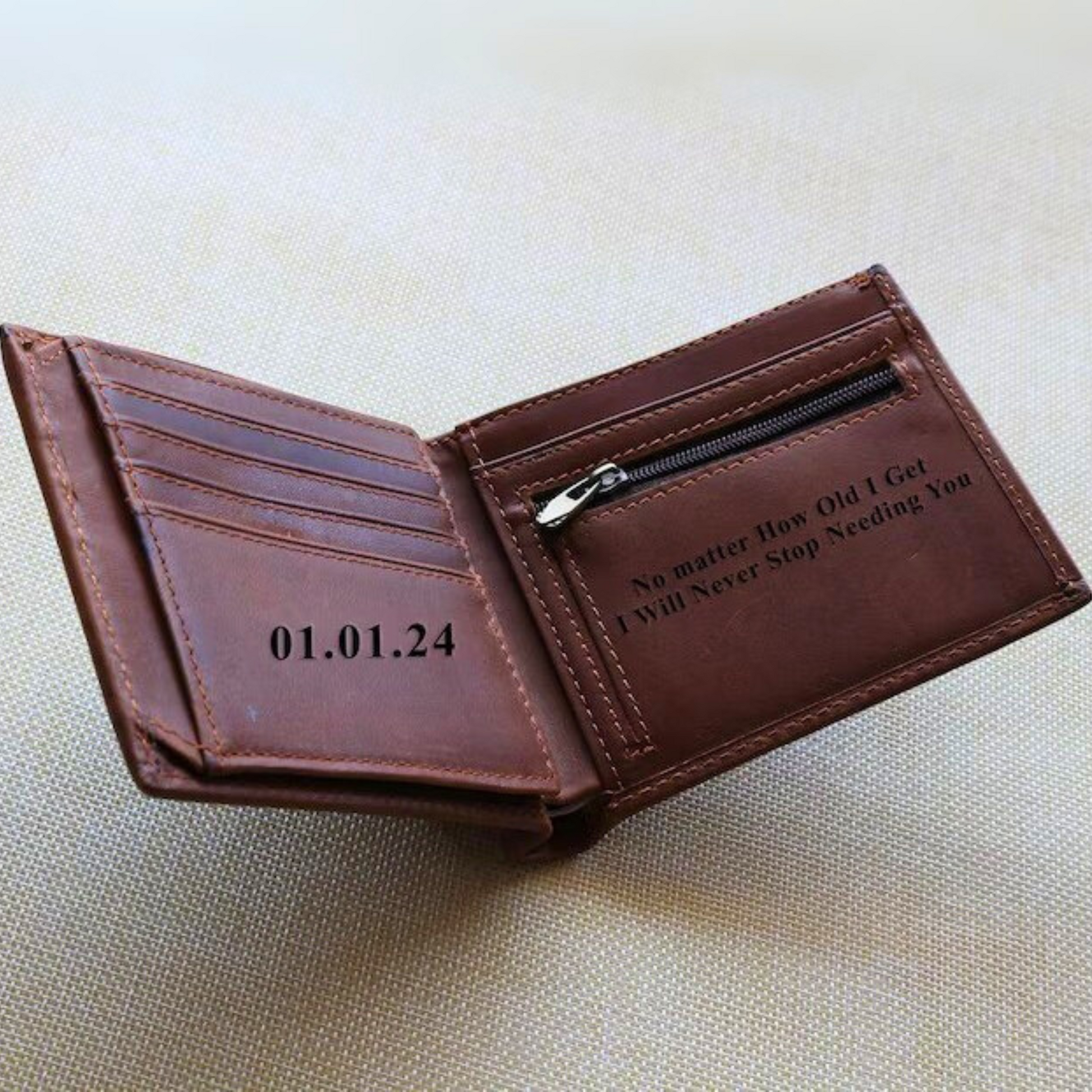 Text engraved on a brown leather wallet with zipper and spacious compartments.