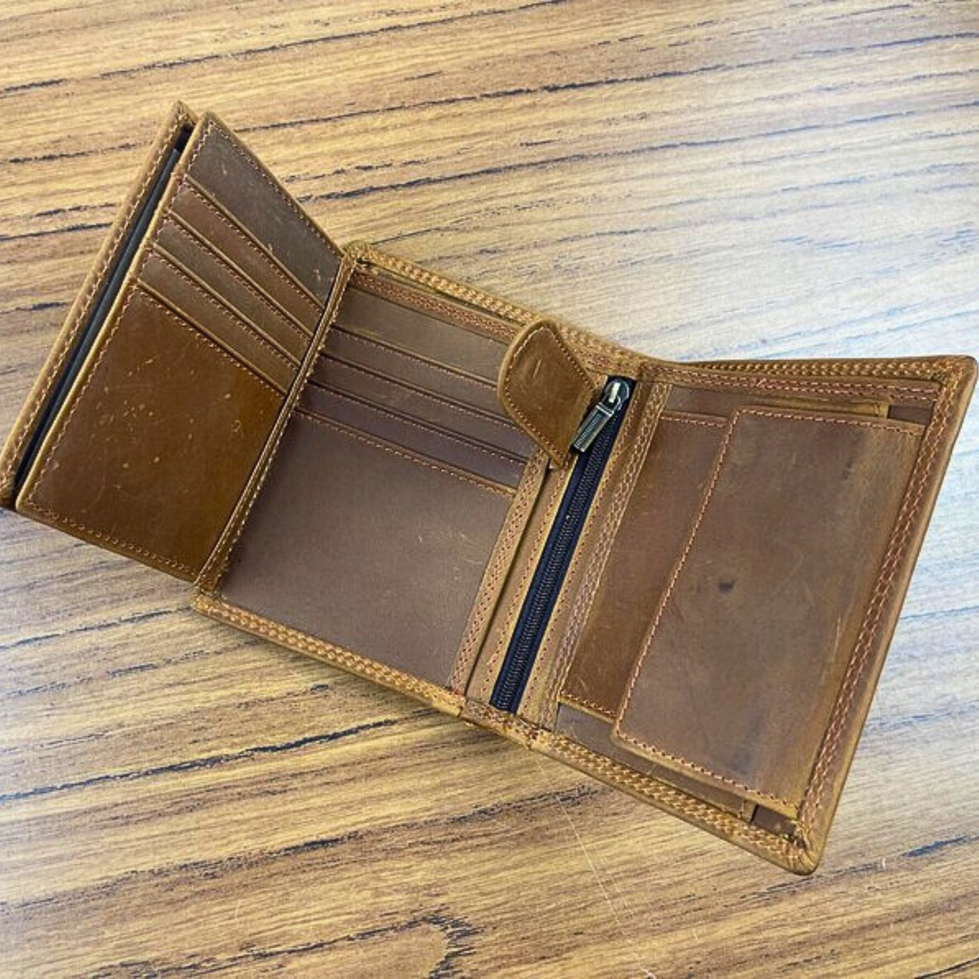 Brown leather trifold wallet with a zipper and various compartments to store cards and money.
