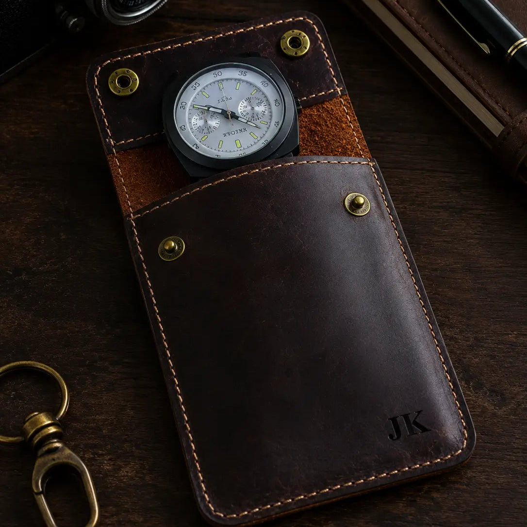 Moody close-up of a personalized dark brown leather watch pouch showcasing detailed stitching, brass snap buttons, and rich leather texture with a luxury craftsmanship aesthetic and partially visible watch.