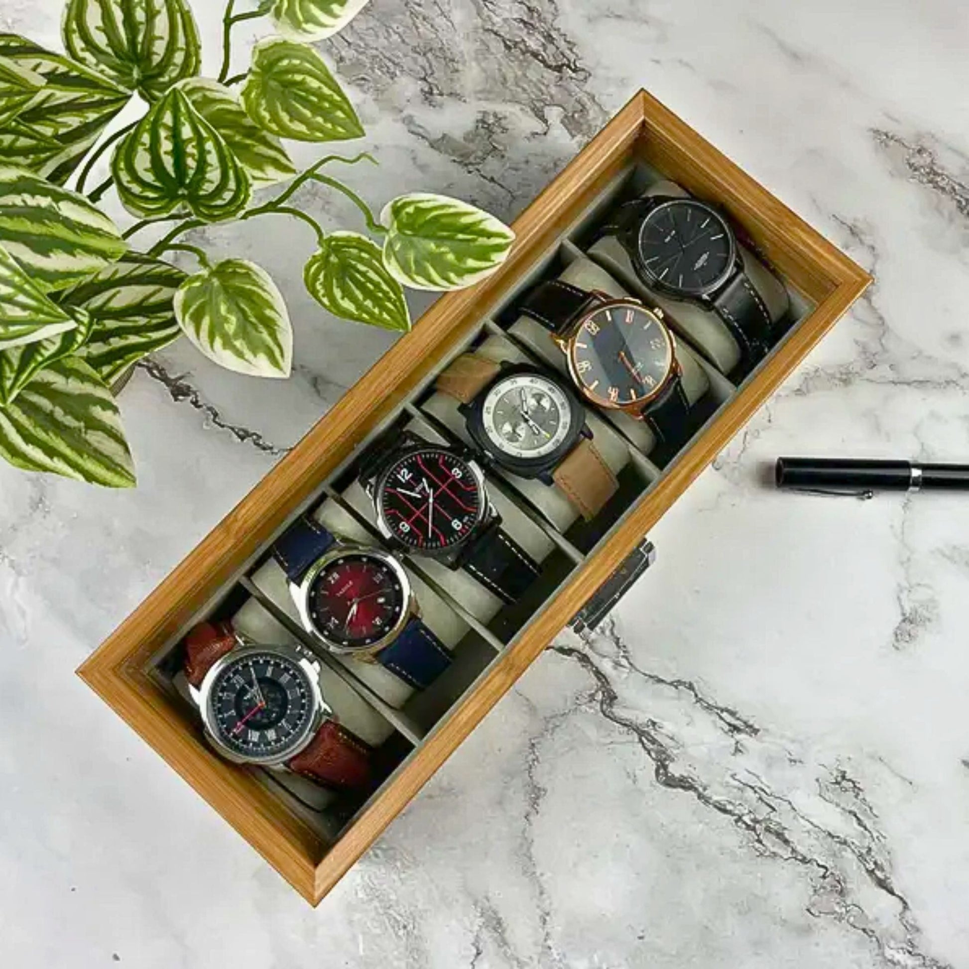 A wooden watch box with six assorted wristwatches arranged neatly, used to organize and elegantly display timepieces.