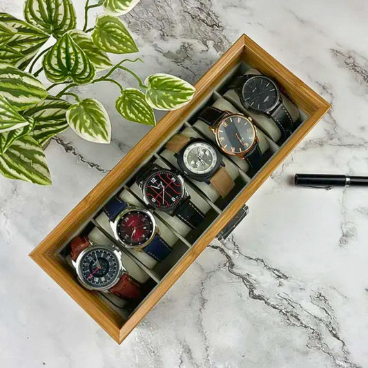 A wooden watch box with six assorted wristwatches arranged neatly, used to organize and elegantly display timepieces.