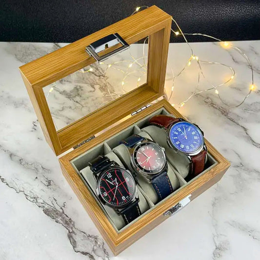 A light brown wooden watch box showcasing three watches, on a marble surface, best to organize and present the watches elegantly.
