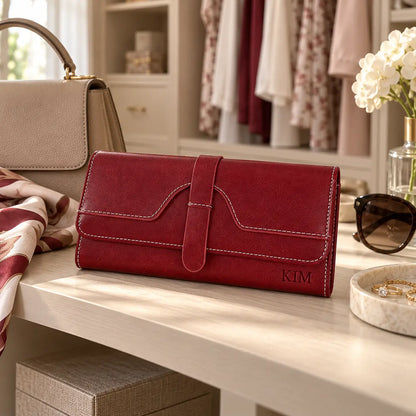 Personalised red women’s wallet engraved with KIM displayed beside beige handbag, sunglasses and scarf