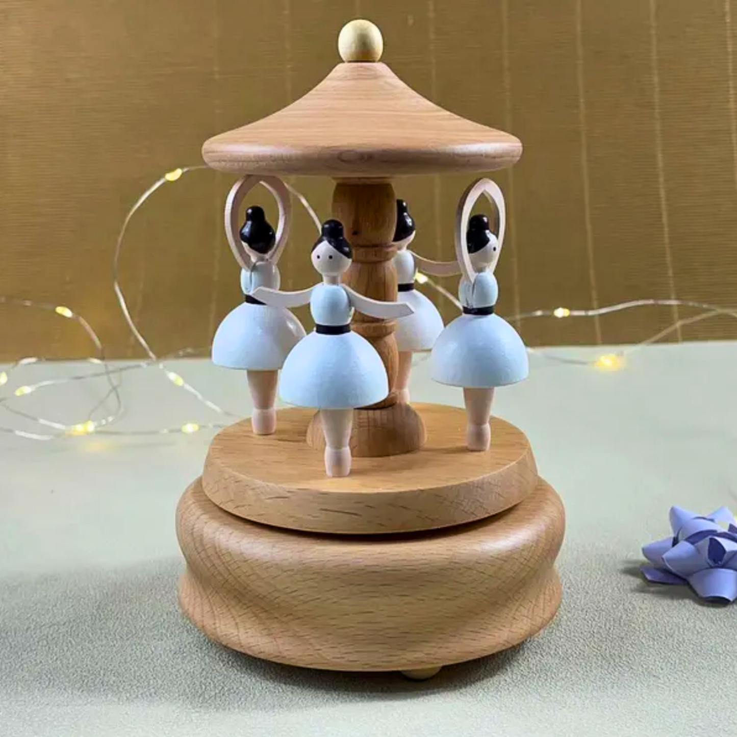 Handmade wooden carousel toy with white ballerina figures, contains music box and also used as a decorative piece.